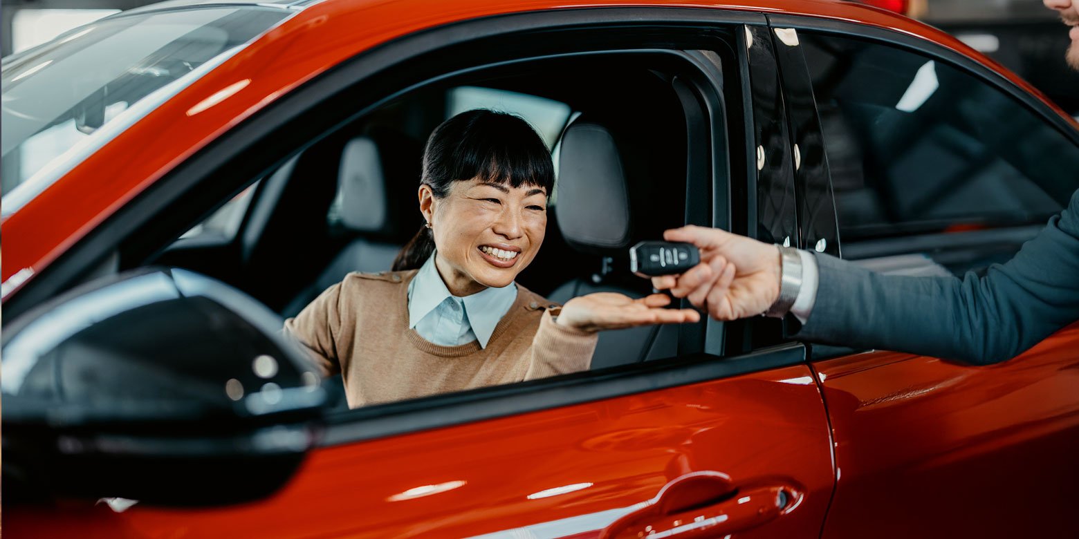 Woman getting handed the keys to a new car