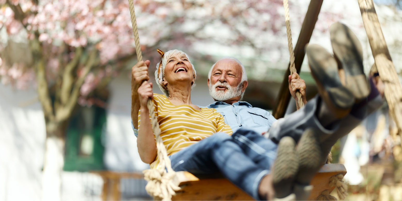 Retired couple smiling on a swing