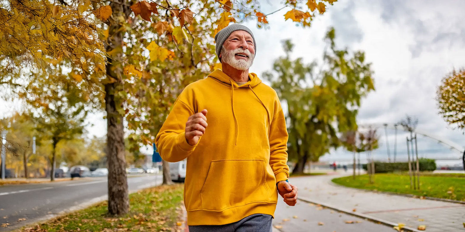 Man with a gray beard jogging in autumn.