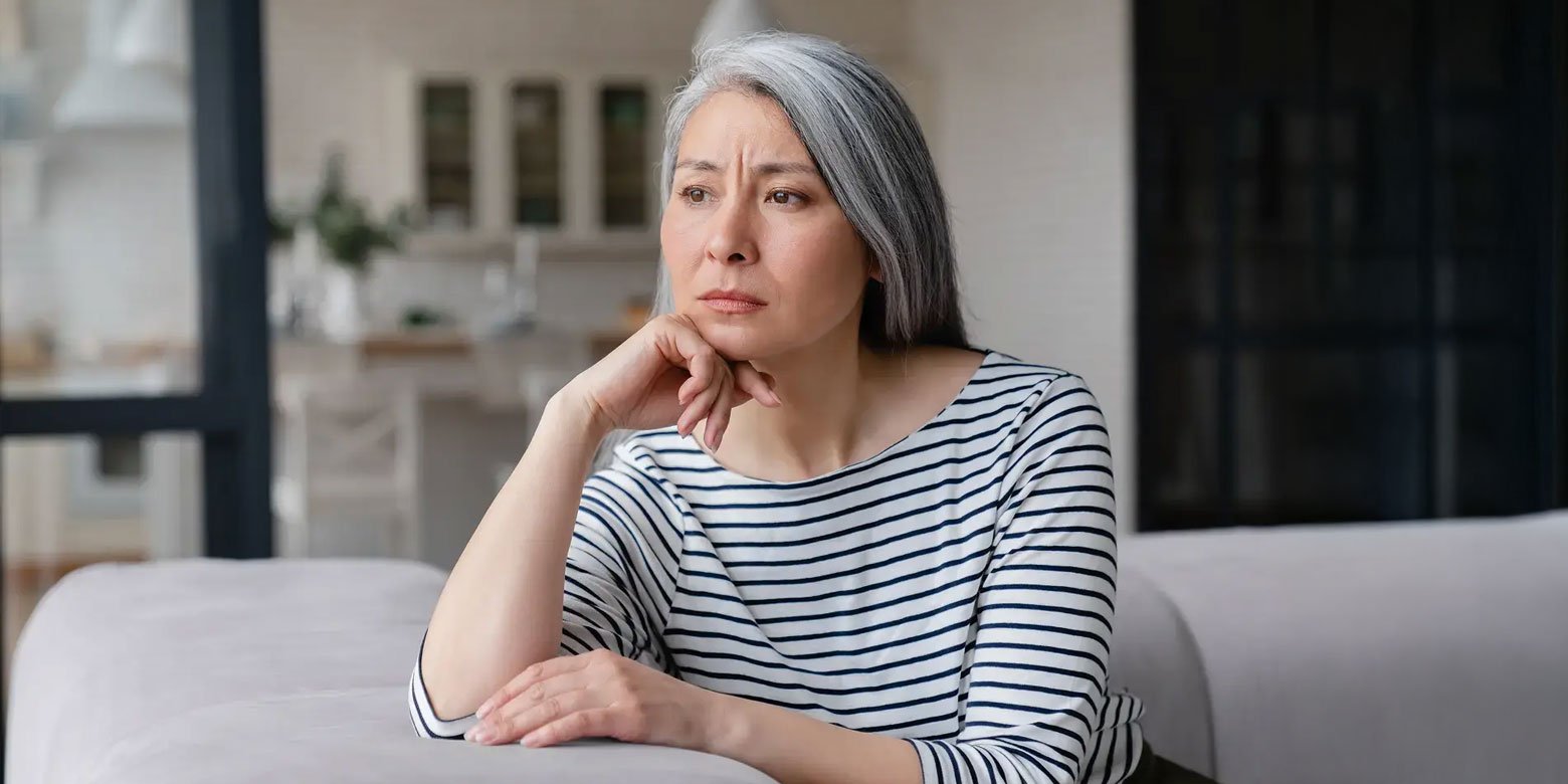 Woman in her 50s thinking on a sofa
