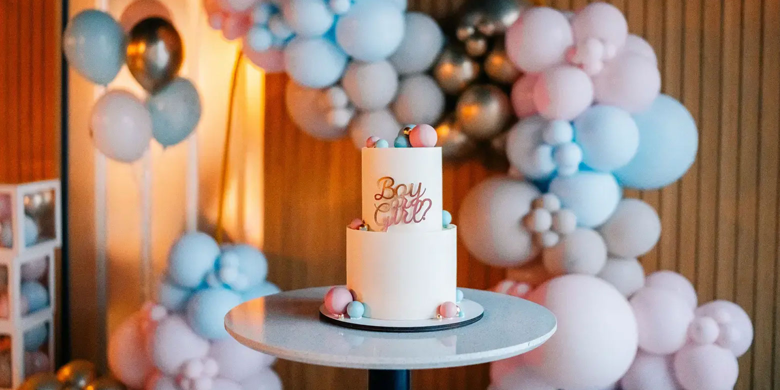Image of a gender reveal cake and balloons
