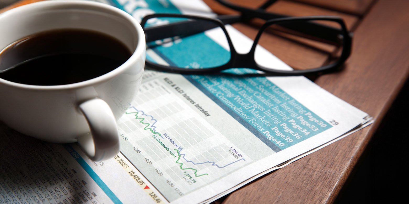 Financial papers on a desk with coffee and reading glasses
