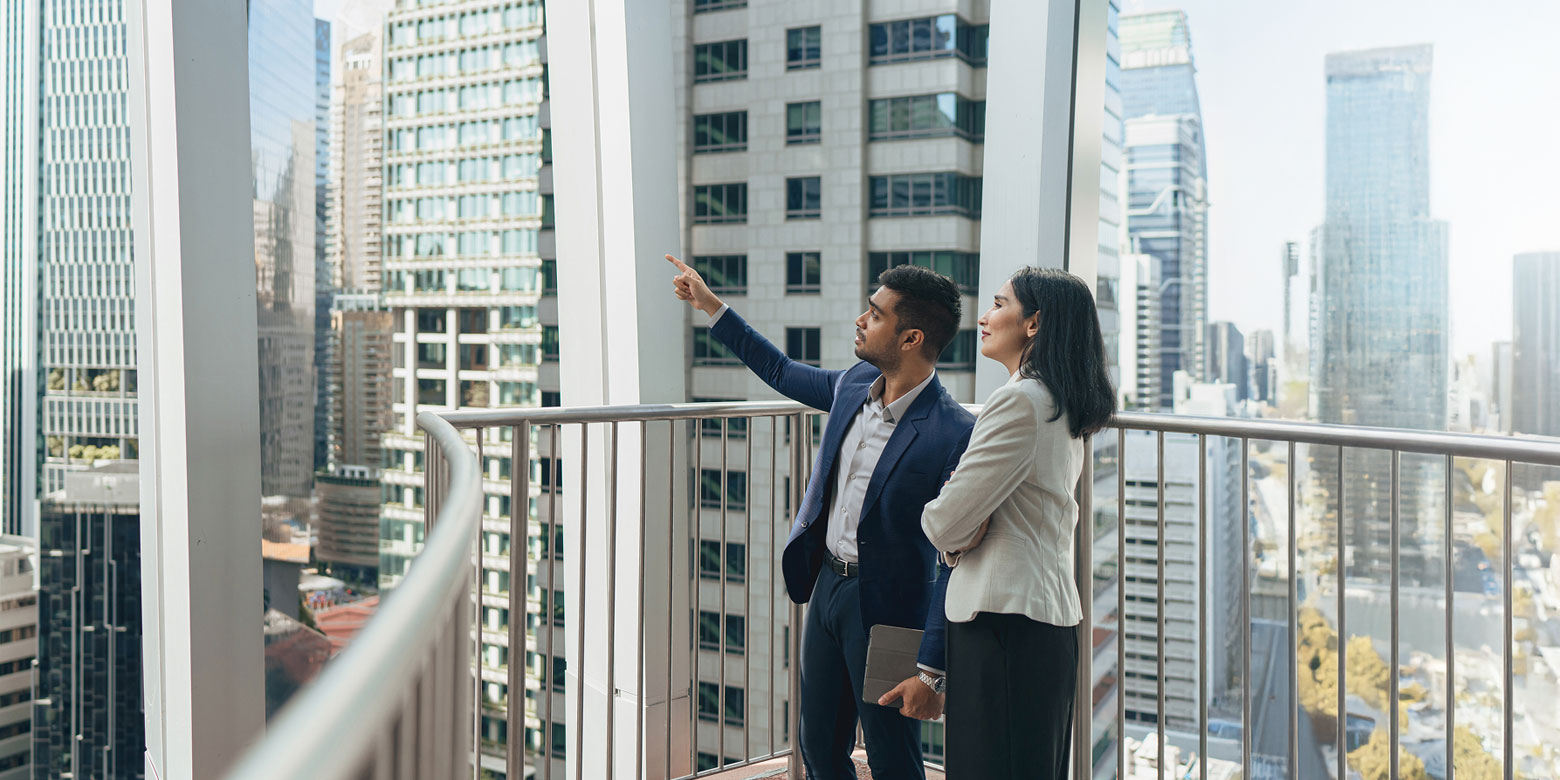 A man talking to a woman on a high-rise balcony pointing upwards