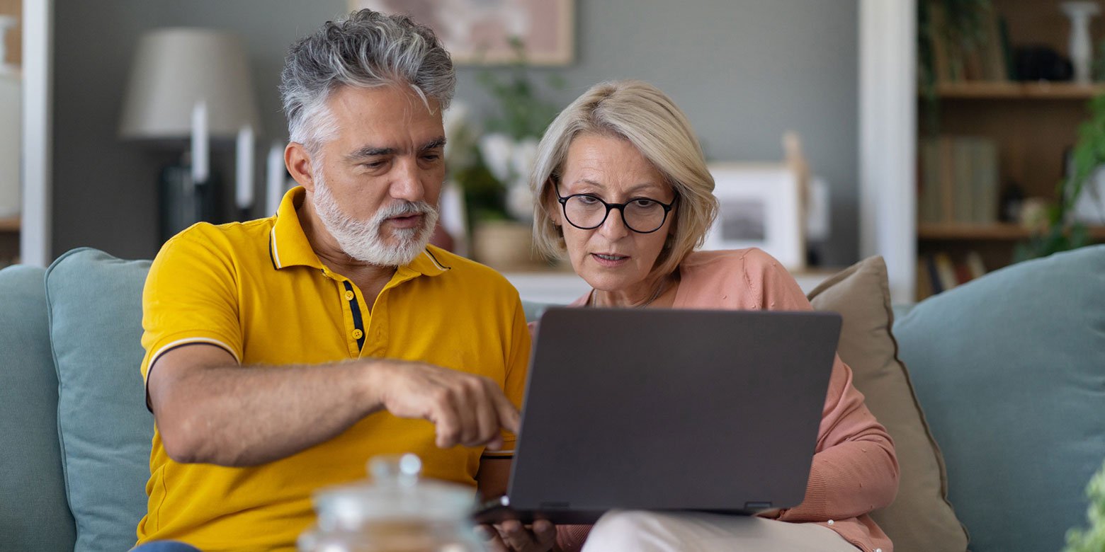 Mature couple looking at a laptop to understand their spousal social security options.