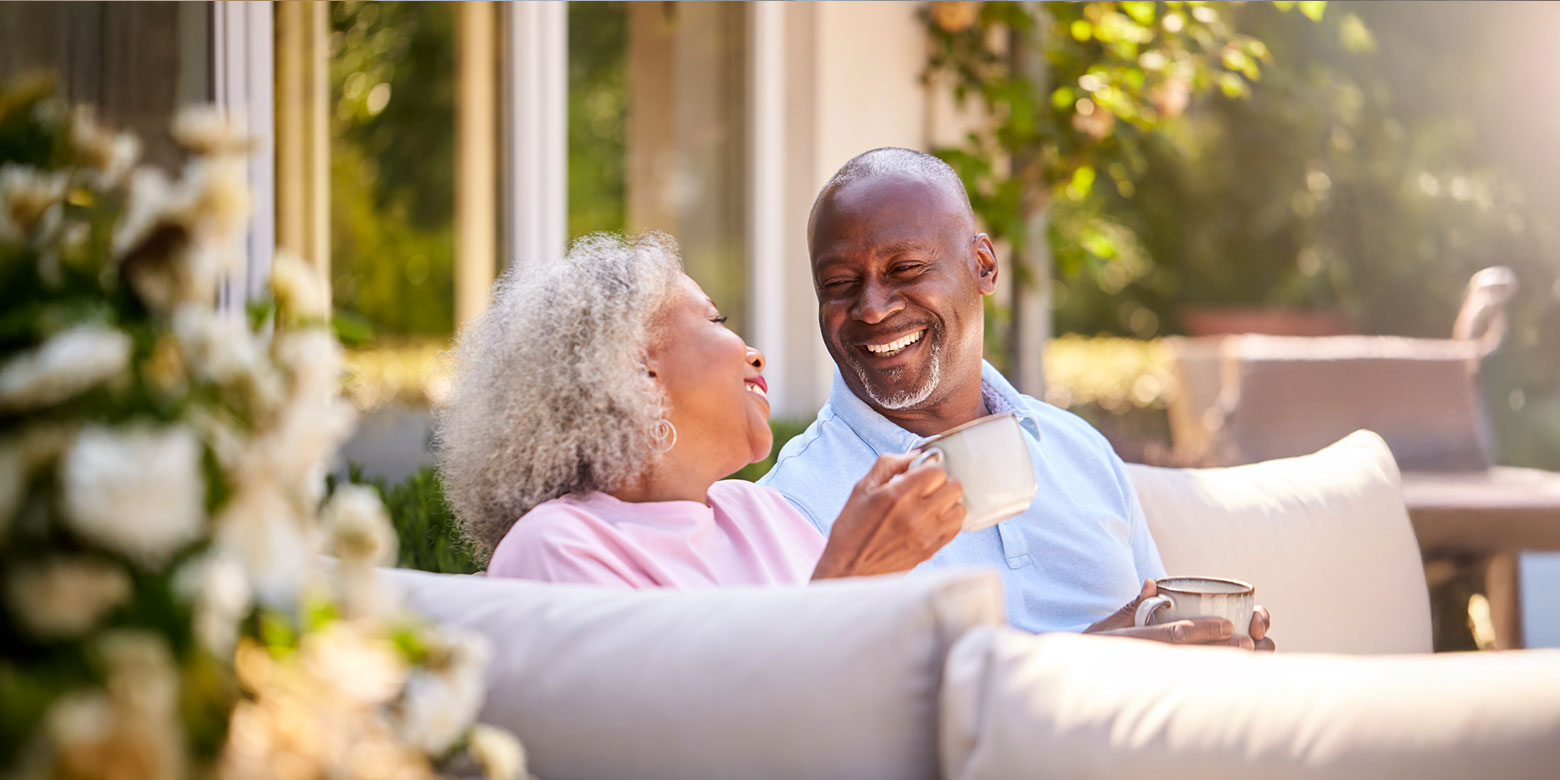 Retired couple drinking coffee and laughing on a porch