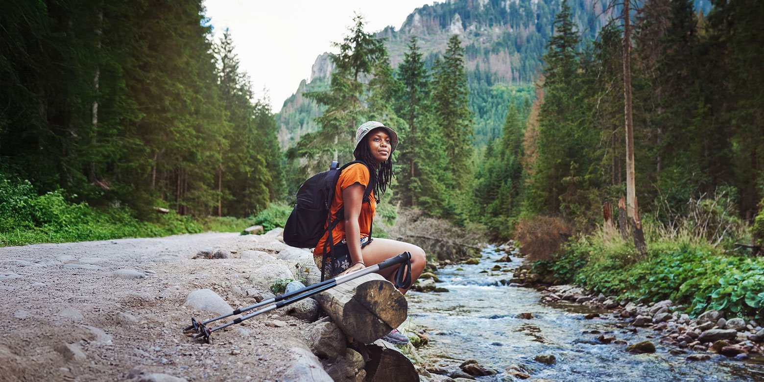 Young adult hiking next to a stream