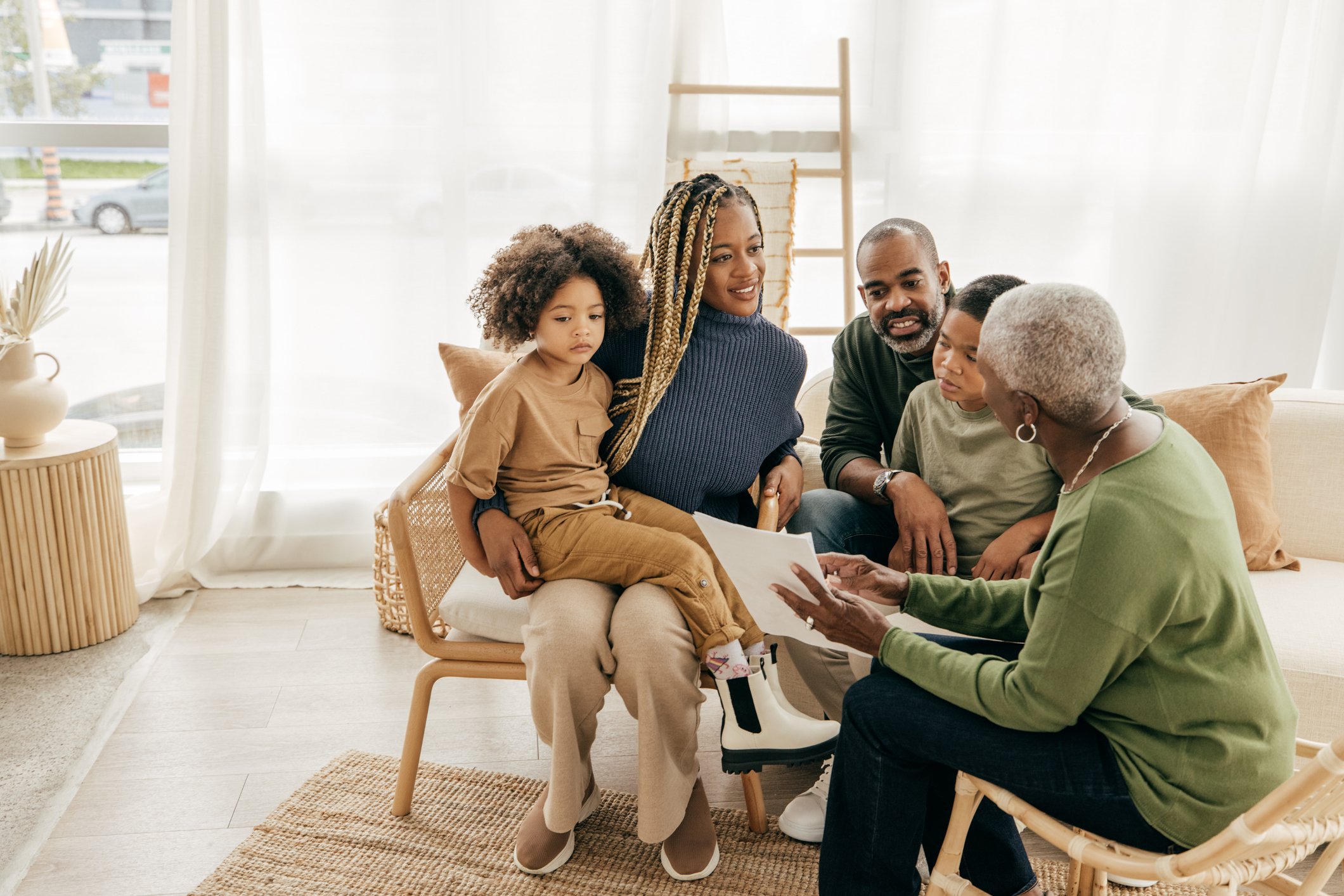a Black family sits and looks at a paper together