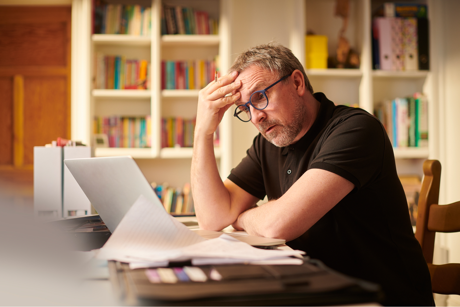 A self-employed person rubs his forehead in frustration as he contemplates his financial plan