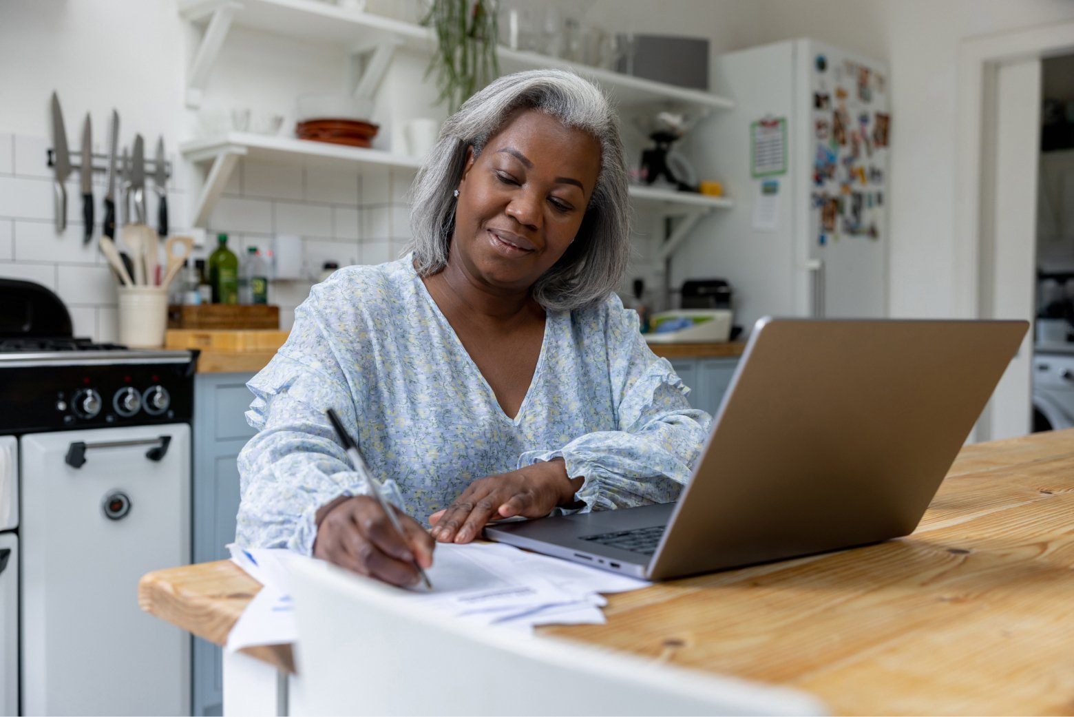 A mature self-employed woman plans her retirement with a solo 401(k) at her kitchen table