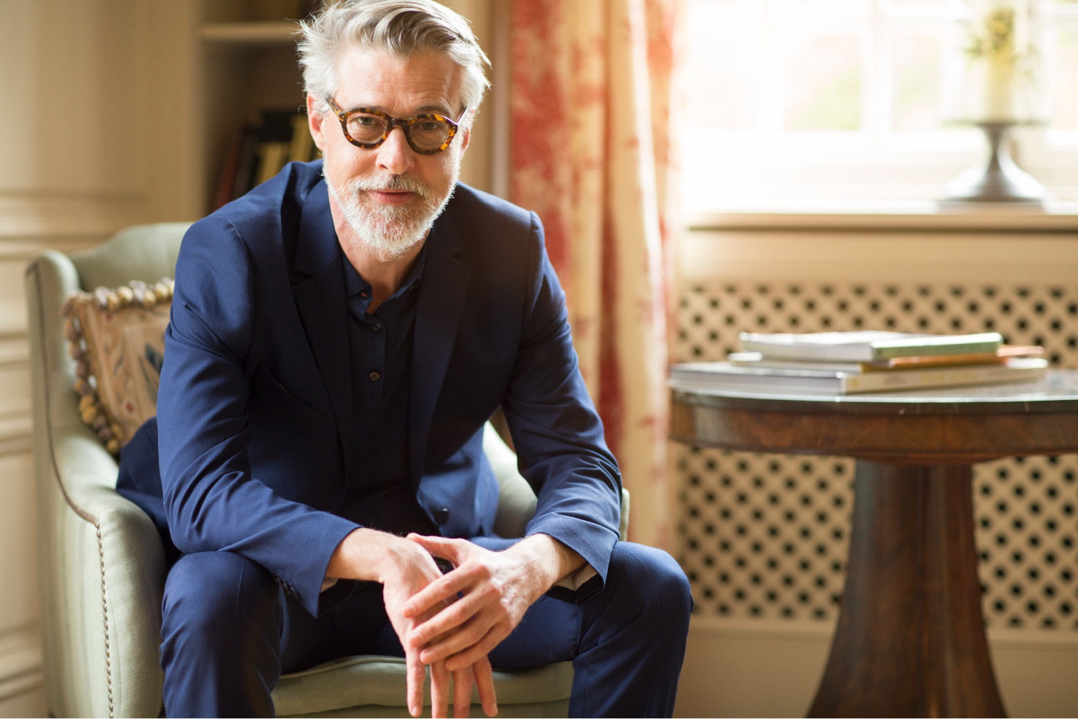 Older man with glasses sitting down looking forward